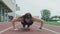 Female athlete doing push ups. Motivated girl exercising at running track