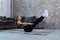 Female athlete doing static abs v hold exercise strengthening core muscles on floor in loft studio