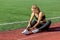 Female athlete experiencing a painful ankle injury while training on a running track