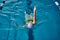 Female athlete in a green-black swimsuit is swimming on his back.