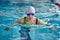 Female athlete in a green-black swimsuit is swimming in the style of breaststroke.