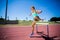 Female athlete jumping above the hurdle