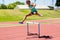 Female athlete jumping above the hurdle