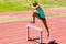 Female athlete jumping above the hurdle