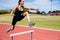 Female athlete jumping above the hurdle