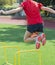 Female athlete jumping over two foot yellow hurdle