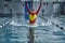 Female athlete in a red-yellow swimsuit makes a jump for joy in the pool.