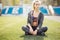 Female athlete resting and relaxing after workout. Relaxed joyful woman sitting down on grass. Healthy lifestyle and happiness con