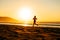 Female athlete running on sunset at beach