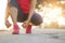 Female athlete tying running shoes on rural street in sunset back