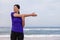 Female athlete warming up and stretching the upper body before running at the beach