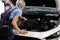 Female auto mechanic examine car engine breakdown problem in auto service, rear view