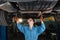 Female auto mechanic working under a car in a garage. Portrait of a concentrated female mechanic. the girl makes an