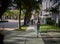 Female with backpack walking on empty sidewalk afternoon light back view