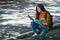 A female backpacker looking for direction on mobile phone and a map while traveling on a mountains road