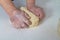 A female baker kneads dough with her hands for modeling dumplings
