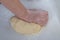 A female baker kneads dough with her hands for modeling dumplings