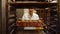 Female baker putting baked michetta in baking trolley