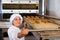 Female bakery worker pulls bread pan out of oven