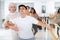 Female ballet teacher showing moves in front of group of different aged dancers in dancing studio