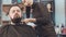 Female barber cuts the beard hair of the male client