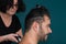 Female barber working with hair clipper, shaving young man\'s neck