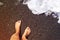 Female bare feet and legs of a teenager on a sandy beach near the sea on a sunny day.