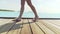 Female bare feet are walking on a wooden bridge. Around the tropical islands and turquoise water.