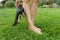 Female barefooted legs on green lawn, woman holding classic heeled shoes. End of the working day, rest, fatigue.