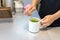 Female barista hand stirring matcha green tea on a mug.