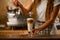 female barista holds glass of macchiato with syrup and sprinkles roasted coffee beans