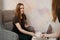 A female barista holds out a latte to a girl in a coffee shop