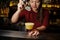 Female bartender adding an ice to the yellow cocktail