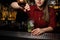 Female bartender adding a liquor to the cocktail