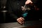 Female bartender serving blue transparent cocktail in the glass placing a golden dry branch