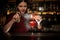 Female bartender spraying on the fire match above the cocktail