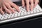 Female beautiful hands with classical French manicure are located over the computer keypad