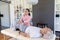 Female biracial physiotherapist stretching caucasian senior man\'s leg lying on table at home