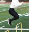 Female in black spandex jumping over two foof high hurdles