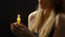 Female blowing burning candle after prayer, releasing negative emotions ritual