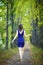 Female in blue dress walking along autumn linden tree alley