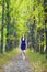 Female in blue dress walking along autumn linden tree alley