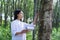 Female botanists in white coat at the forest.Young asian scientist woman looking at the bark of the rubber tree and make notes to