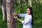 Female botanists in white coat at the forest.Young asian scientist woman looking at the bark of the rubber tree and measure the