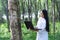 Female botanists in white coat with laptop at the forest.Young beautiful asian scientist woman looking at the bark of the rubber