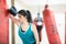 Female boxer taking a break, tired after a workout, leaning her elbow on a boxing bag