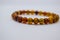 The female bracelet, made of small amber stones, rests on a white background