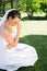 Female bride sitting on grass in park