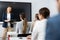 Female business coach gesturing with hand while standing against group of people sitting at chairs in front of her