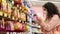 female buyer is choosing sweets and snacks in supermarket at pandemic